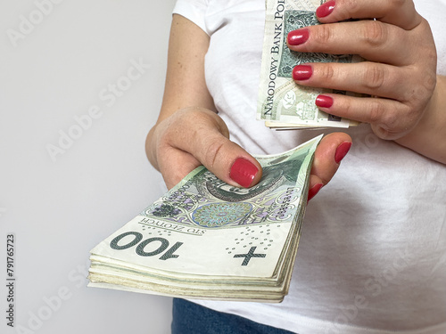 Stack of Polish zloty zl pln paper bills in female hands isolated on white
