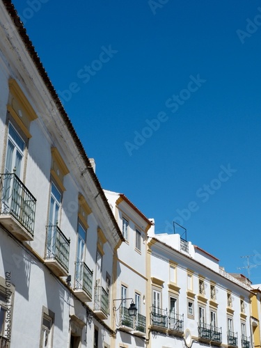 Line of old fashioned vintage facades of white colour against clear sky in Evora Portugal vertical backdrop