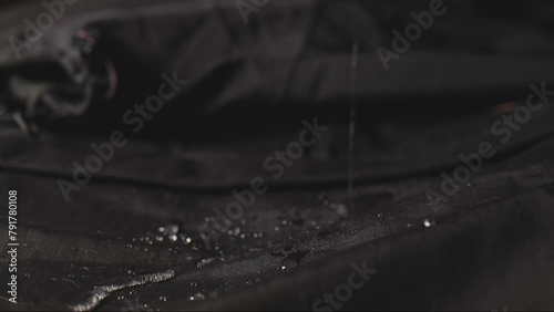 Water dripping onto waterproof fabric. Water jet on water resistant jacket. drops of water on water-repellent clothing