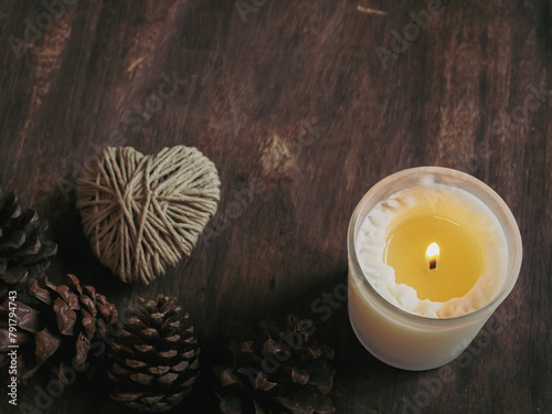 Scented candles with yarn hearts and pine cones on a vintage old wooden background for relaxation.