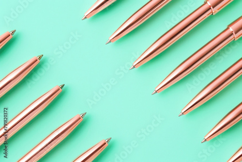 Assorted pens and pencils with labels on turquoise background for office supplies and writing tools concept photo
