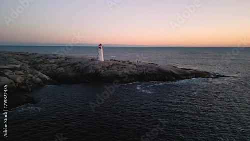 Peggy's Cove Lighthouse at dusk Nova Scotia Canada. As the sky transforms into a canvas soft pastel hues, lighthouse emerges as symbol resilience and hope, guiding sailors home with its steadfast glow photo