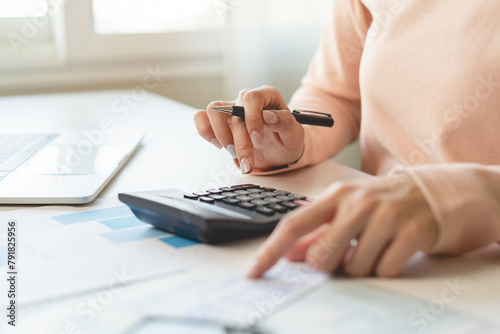 Deduction planning, debt asian young woman  hand using calculator to calculating money balance from bill and income, cost budget expenses for pay money form personal individual on table at home. © Pormezz