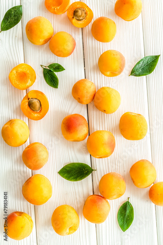 Apricots and leaves pattern on white wooden background top view