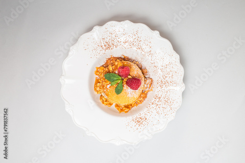 Top view of a stack of pancakes with raspberries and mint on white plate photo