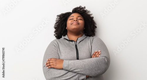 A woman with her eyes closed in contentment, arms crossed over her chest, finds a moment of serene solitude against a minimalist white background.