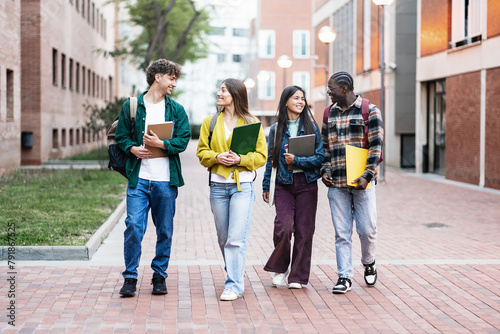 Group of student friends walking on college campus, chatting and laughing after university classes photo