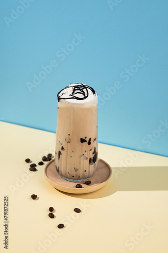 Iced coffee latte with chocolate in a tall glass with a milk on a blue and yellow background