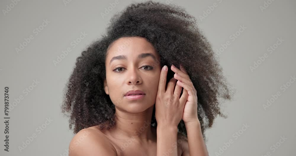 Beauty and Healthcare concept - Beautiful African American woman with curly afro hairstyle hair and clean, healthy skin on gray studio background posing and looking at camera Beauty and Healthcare concept - Beautiful African American woman with curly afro hairstyle hair and clean, healthy skin on gray studio background posing and looking at camera