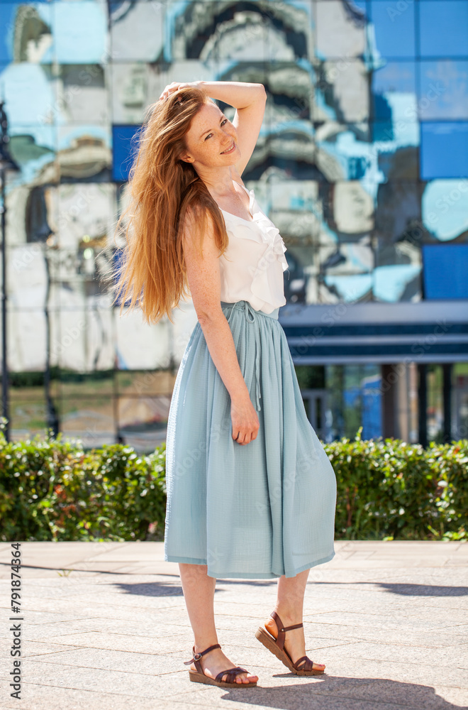Full body portrait of a young beautiful red hair woman in a summer street
