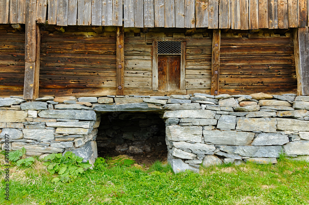 An old wooden barn, mounted on a rugged stone foundation, stands testament to timeless rural craftsmanship.