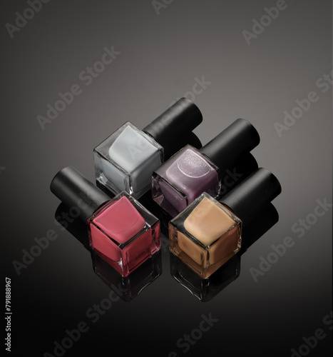 Nail polish Bottles of pastel colors on a dark background with reflections.