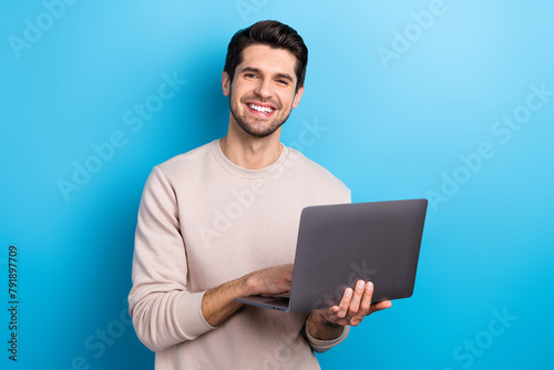 Photo of young nice man use wireless laptop coworking wear beige sweatshirt isolated on blue color background