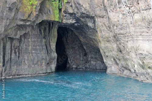 Rocks and caves of the coast near the famous spireTrøllkonufingur towering rock formation on Vágar Island