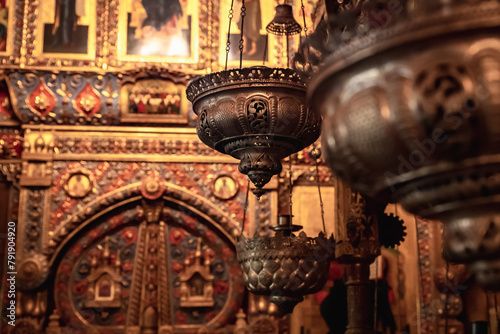 Censers hang in a row against the backdrop of an expensively decorated altar with icons. Everything in gold, bronze and painting photo