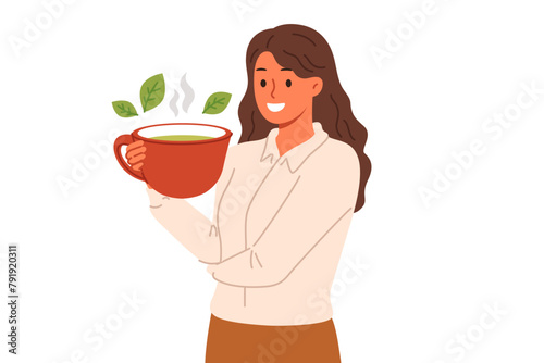 Woman drinks green loose leaf tea from large mug, enjoying bite of hot, soothing drink. Ceylon aromatic tea with mint and herbs in hand of business lady taking break while working or studying