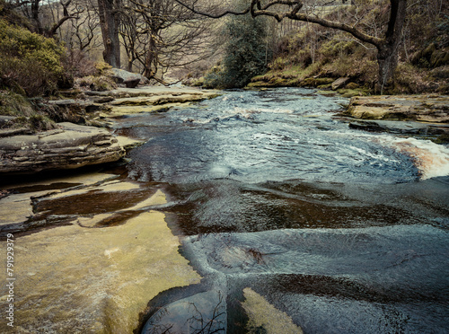 Stream in the forest. A little river stream running down some rocks, stone path between the forest trees. Moorland English scene. photo