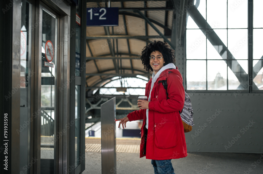 Obraz premium Curly-haired young guy in red jacket at the railway station