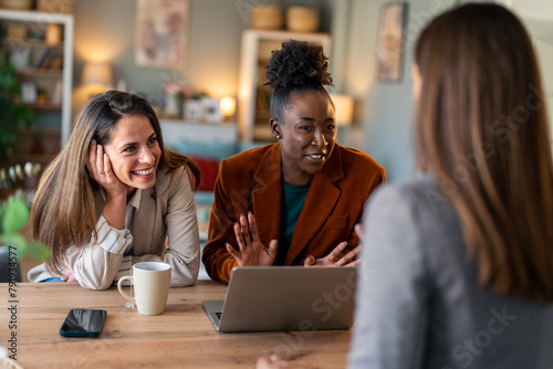 Group of happy diverse business women smiling while sitting together in an office.