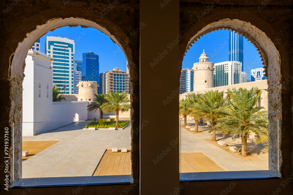 View through arched windows at Qasr Al Hosn fort of the historic Arabic castle and modern skyline of Abu Dhabi, United Arab Emirates.