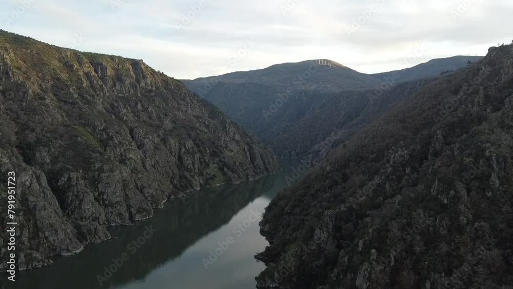Aerial drone shot gliding over River Sil amidst Cañones del Sil, framed by warm sunset hues between two mountains
Aerial drone shot gliding over River Sil amidst Cañones del Sil, framed by warm sunset hues between two mountains