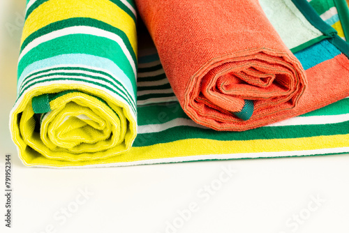 Large size, two colorful beach towels rolled on white surface