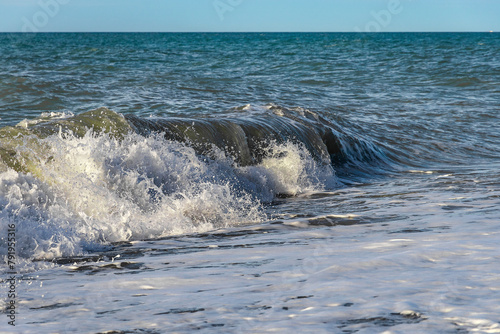 Close-up of a wave on the Black Sea coast. Coastal waves. Selective focus. View of the waves of the Black Sea. Clear wavy sea water. Splashes of waves break on the rocks. Sea surf on the beach.