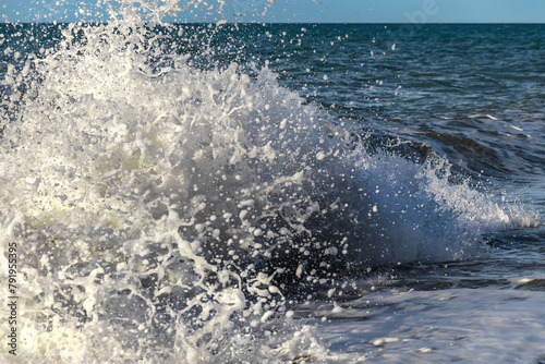 Splashes of sea waves. Large waves that occur during stormy weather break against the concrete four-legged supports of the breakwater. Spray breaks off from powerful waves.