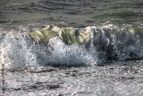 Coastal waves. Selective focus. View of the waves of the Black Sea. Clear wavy sea water. Splashes of waves break on the rocks. Sea surf on the beach. The power of water on the sea surf.