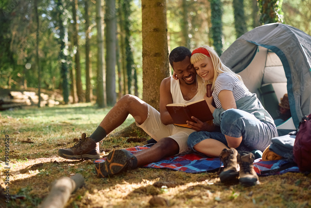 Happy couple reading book while camping in nature. Happy couple reading book while camping in nature.