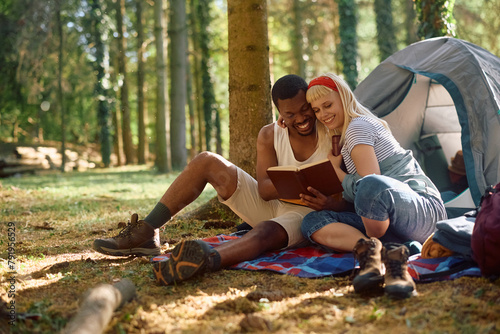 Happy couple reading book while camping in nature.