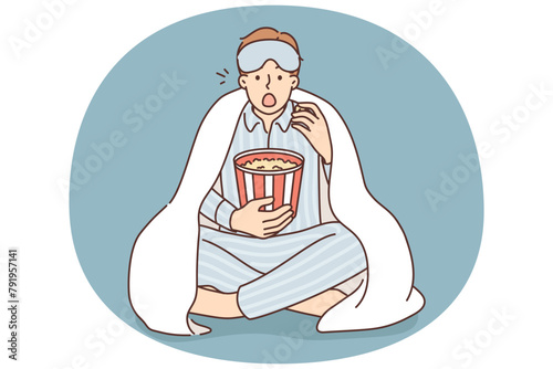 Man in pajama eat popcorn watch movie