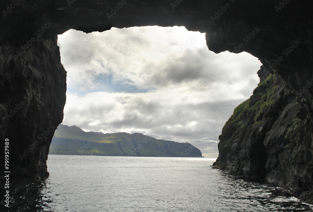 Rocks and caves of the coast near the famous spireTrøllkonufingur  towering rock formation on Vágar Island