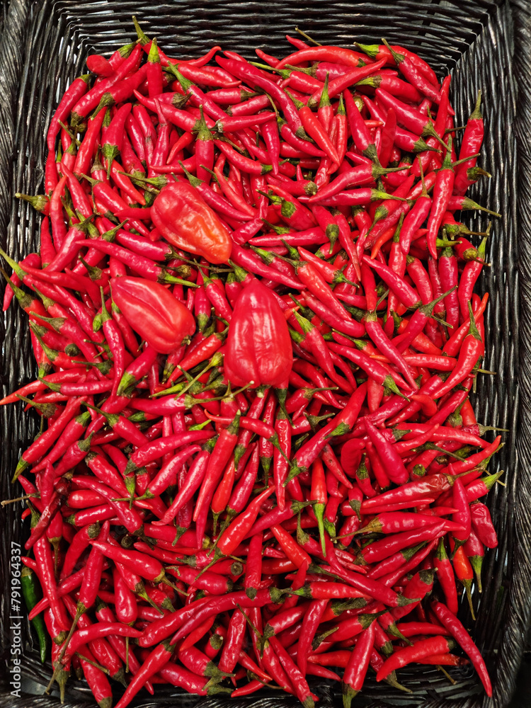 Naklejka premium Lot of red chili peppers or cayenne peppers in the wicker basket. Top view.