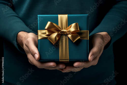 hand holding a present box with gold bow on dark background, in the style of dark teal and dark indigo сreated with Generative Ai