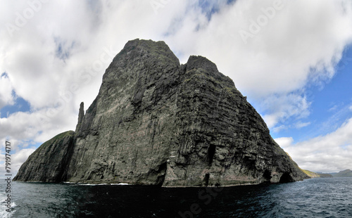 Rocks and caves of the coast near the famous spireTrøllkonufingur  towering rock formation on Vágar Island photo