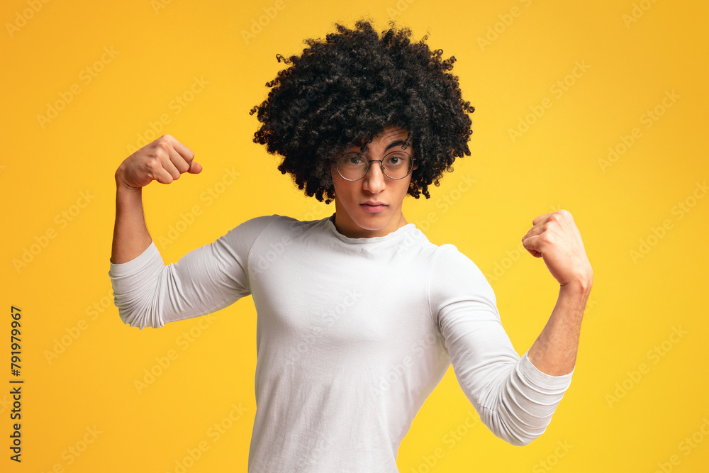 Awesome strong black guy showing biceps on orange background