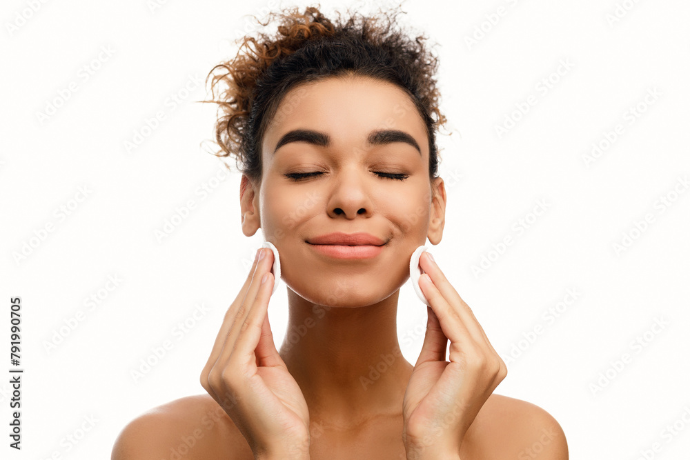Young woman cleaning her face with cotton pads Young woman cleaning her face with cotton pads