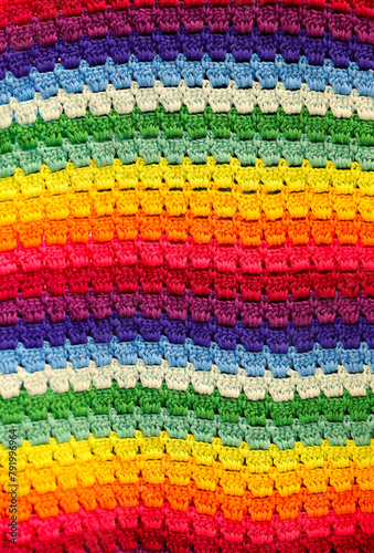 background of colorful crocheted blanket with a rainbow pattern photo