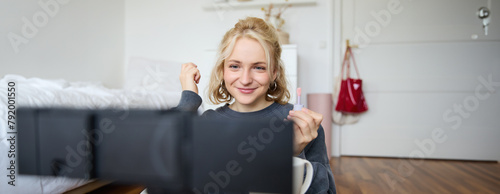 Image of happy, beautiful young social media influencer, female vlogger records a video on digital camera, tutorial on how to put makeup, getting ready for going out, talking to followers