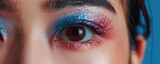 close-up of a woman's eye adorned with colorful, fine glitter makeup, highlighting the details in her eye.