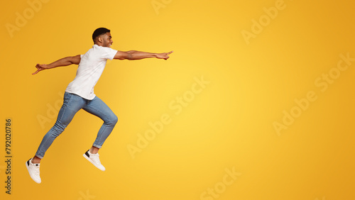 Happy african guy jumping in air, reaching hand aside to free space