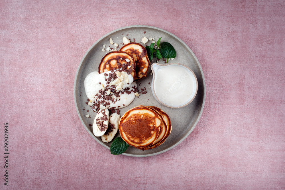 Traditional American Pancakes with banana honey cream, macadamia nuts and chocolate crumbles served as top view on a Nordic design plate Traditional American Pancakes with banana honey cream, macadamia nuts and chocolate crumbles served as top view on a Nordic design plate