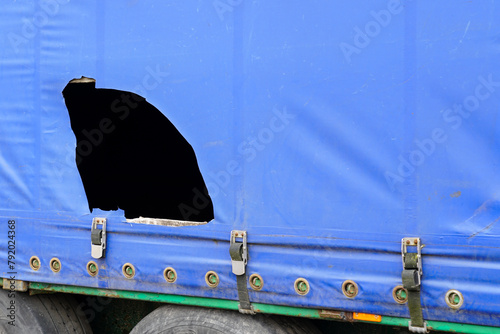 Truck trailer with blue damaged awning, cargo goods theft problem by cutting the awning, cut awning