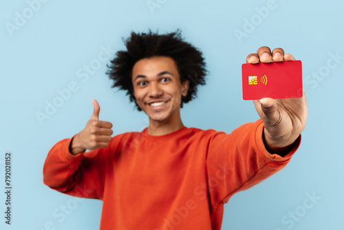Happy man showing credit card and thumbs up photo