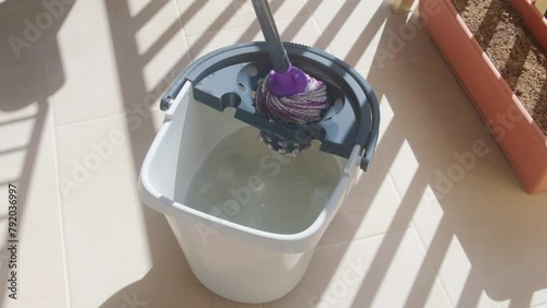 Wringing out a mop in a plastic bucket. photo