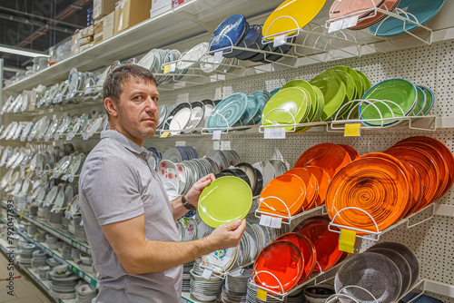A man chooses dishes at a home improvement store. Kitchen utensils.