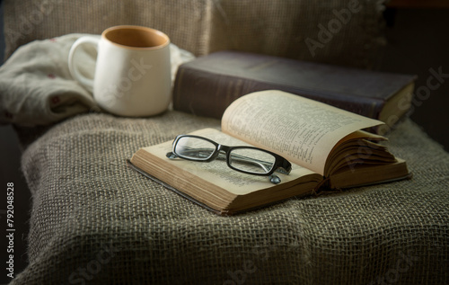 The glasses are on an old book. There is a mug and a burlap bag next to it