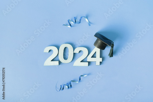 Class of 2024 concept. Wooden number 2024 with graduated cap and confetti