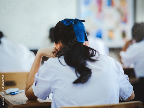 Students reading exam answer sheets exercises in classroom of school with headache.and stress